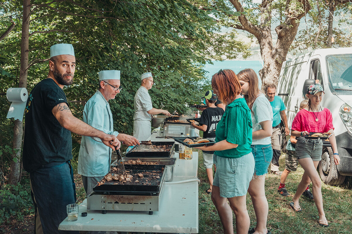 Restauration assurée par les cuisiniers de Savines pour 250 personnes. Grillades et salades, servies par les bénévoles.  Festival Partir en livre au village vacances CCAS de Savines-le-Lac (Hautes-Alpes), le 3 août 2023.