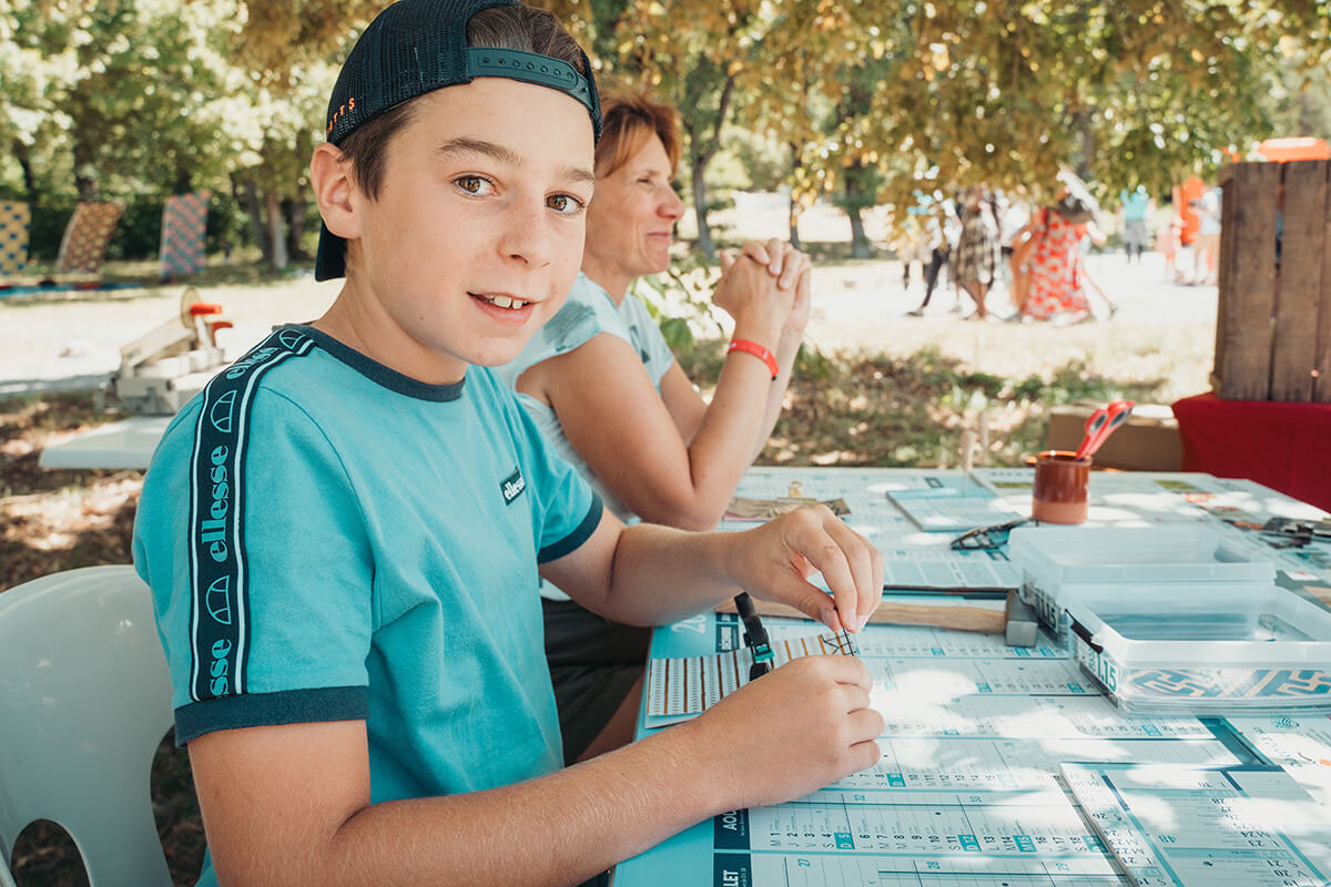 Louis, 11 ans (CMCAS Marseille), à l'atelier reliure avec Edith Pophillat-Casotti, de l’atelier « reliures & cimes ». Festival Partir en livre au village vacances CCAS de Savines-le-Lac (Hautes-Alpes), le 3 août 2023.
