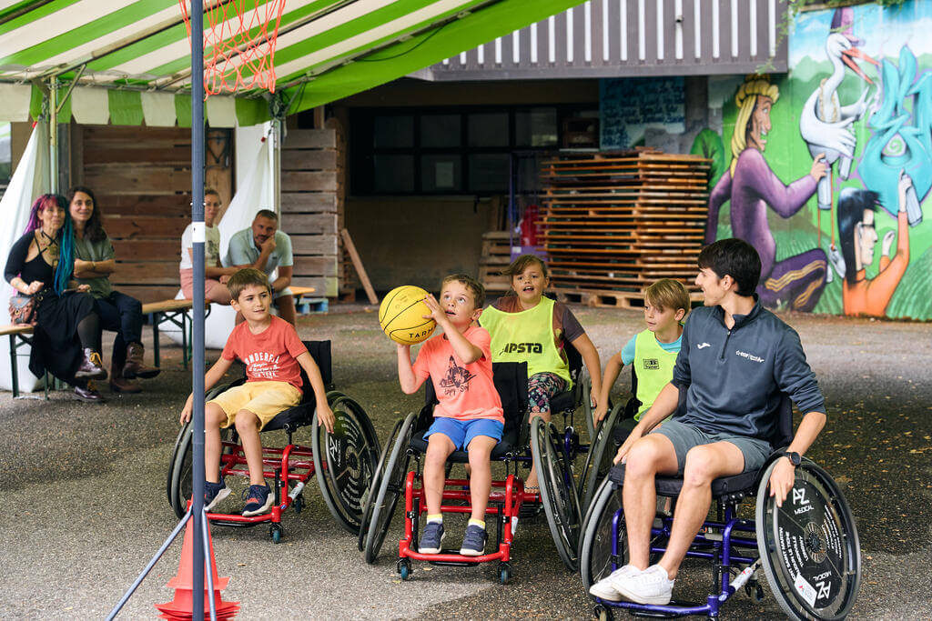 Basket-fauteuil avec Baptiste Wolf, du Comité régional handisport Grand Est. Fête des Papillons dédiée à la sensibilisation au handicap au centre CCAS de Kaysersberg, août 2023.