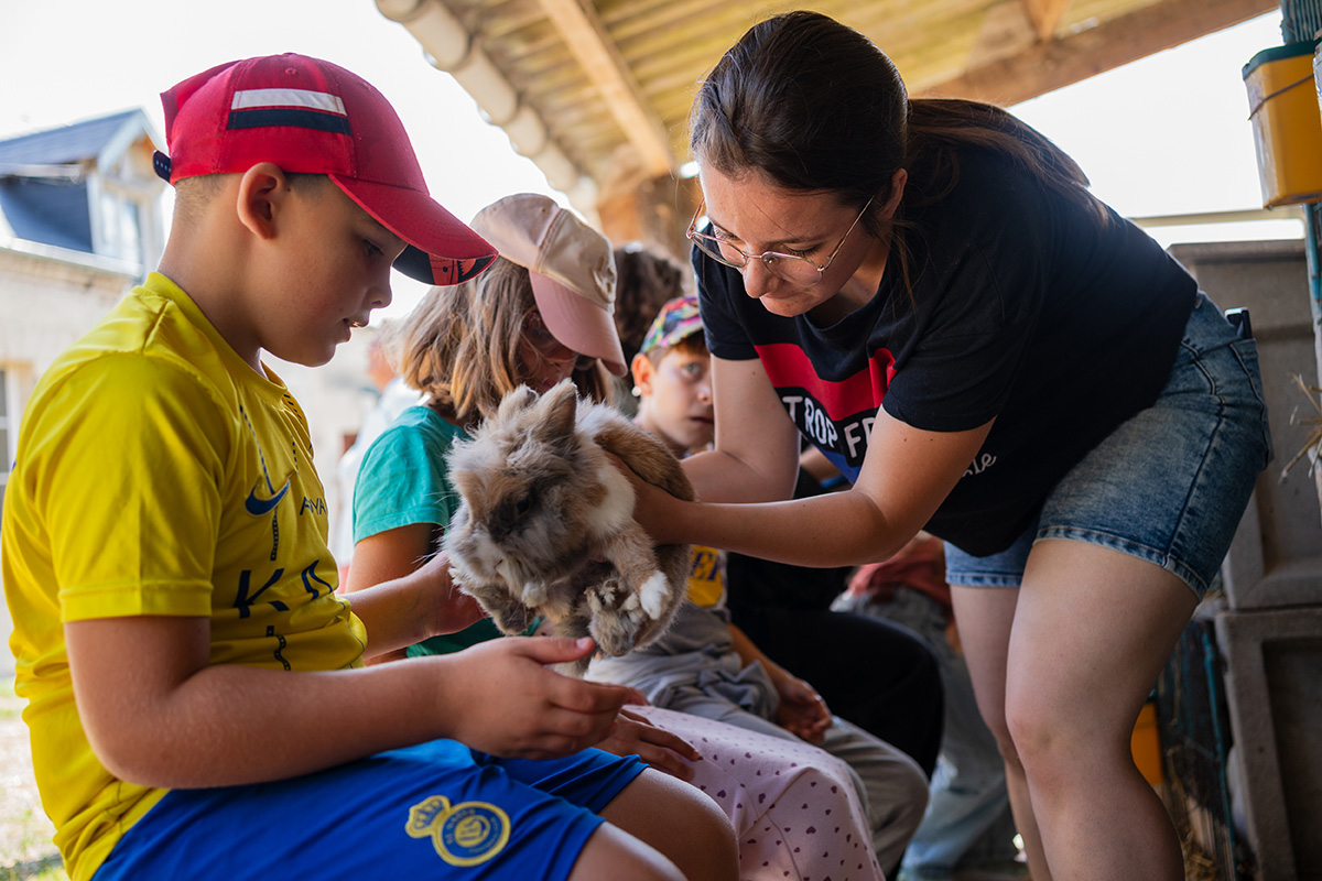 Colo petits soigneurs : des vacances pour s’occuper des animaux | Journal des Activités Sociales de l'énergie Les caresses aux lapins. Colonie de vacances CCAS/CMCAS Petits soigneurs pour les enfants de 4 à 8 ans de l'Île de France, du Nord Pas-de-Calais et de Picardie, à Merlieux-et-Fouquerolles dans l'Aisne, juillet 2025.